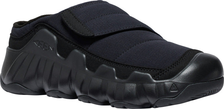 A black slip-on shoe with a thick sole and a velcro strap.