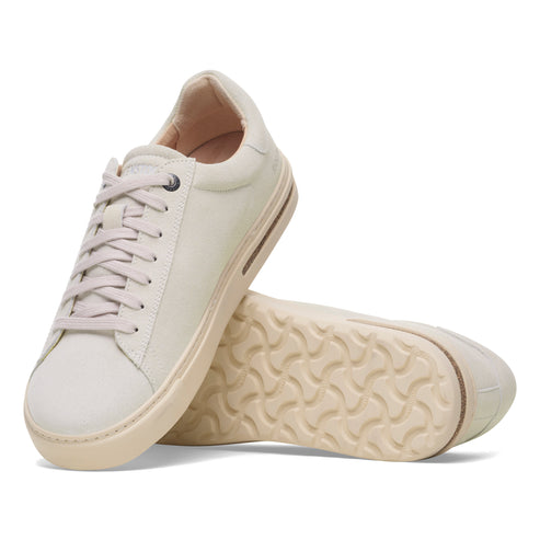 Two off-white casual sneakers with laces, one standing upright and the other lying on its side showing the patterned sole.