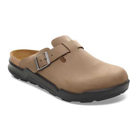 Taupe clog shoe with black soles and adjustable buckle.