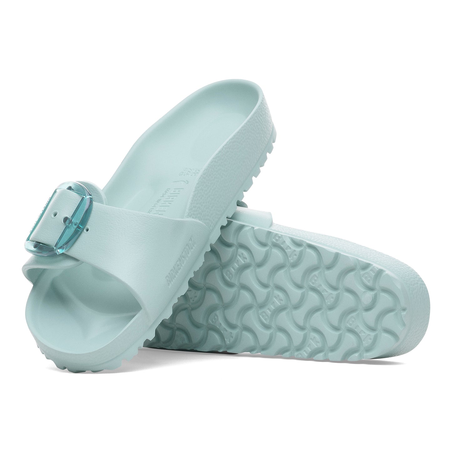 Two mint green slide sandals with a translucent buckle lying on their sides.