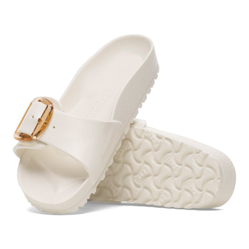 Pair of white slide sandals with large gold buckle.