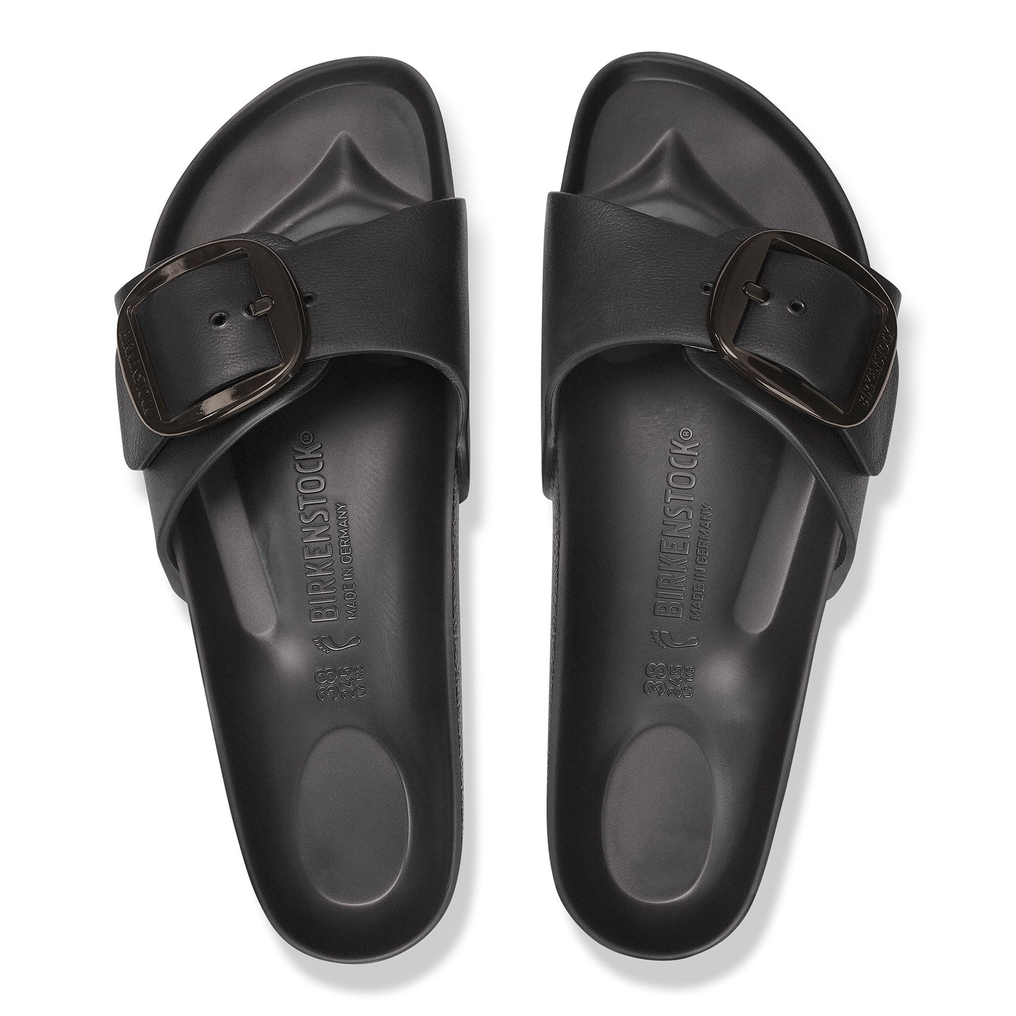 Overhead view of two black, molded plastic sandals with large buckles.