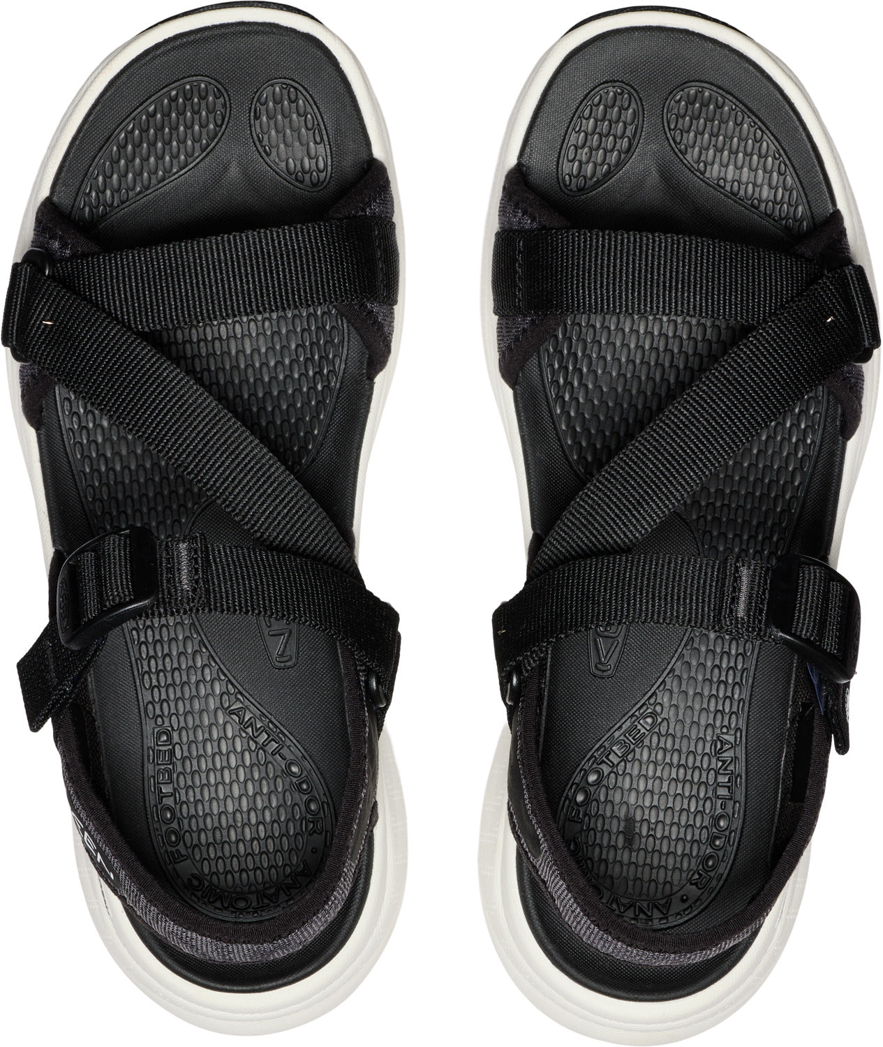 Top-down view of black sandals with white soles, featuring a criss-cross strap design and buckle closures.