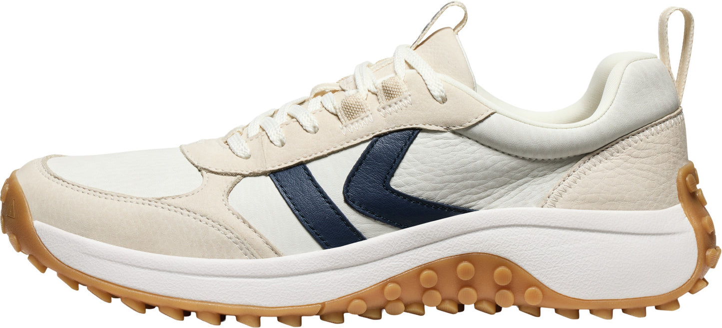 A low-top sneaker with a tan sole and white upper, featuring a navy blue chevron on the side.