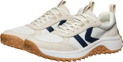 A pair of low-top sneakers with white and cream panels, navy blue side detail, off-white laces and tan soles.