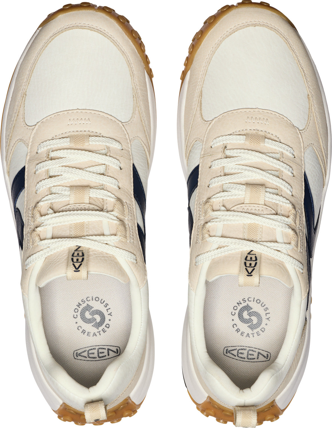 Top-down view of two off-white sneakers with navy blue side stripes, off-white laces, white soles, and brown rubber outsoles. "KEEN" and a circular icon with "CONSCIOUSLY CREATED" are visible on the insole.