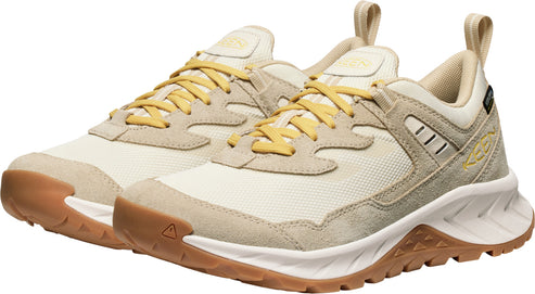 A pair of low-cut athletic shoes with yellow laces and cream-colored suede and fabric uppers. They have tan rubber soles with brown triangle-shaped treads.