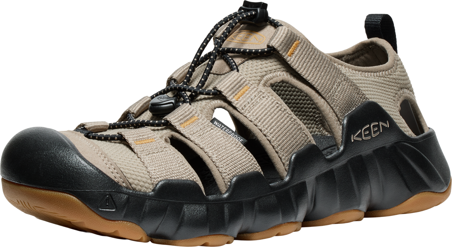 Beige sandal with a dark toe cap, open design, black sole, and bungee lacing system.