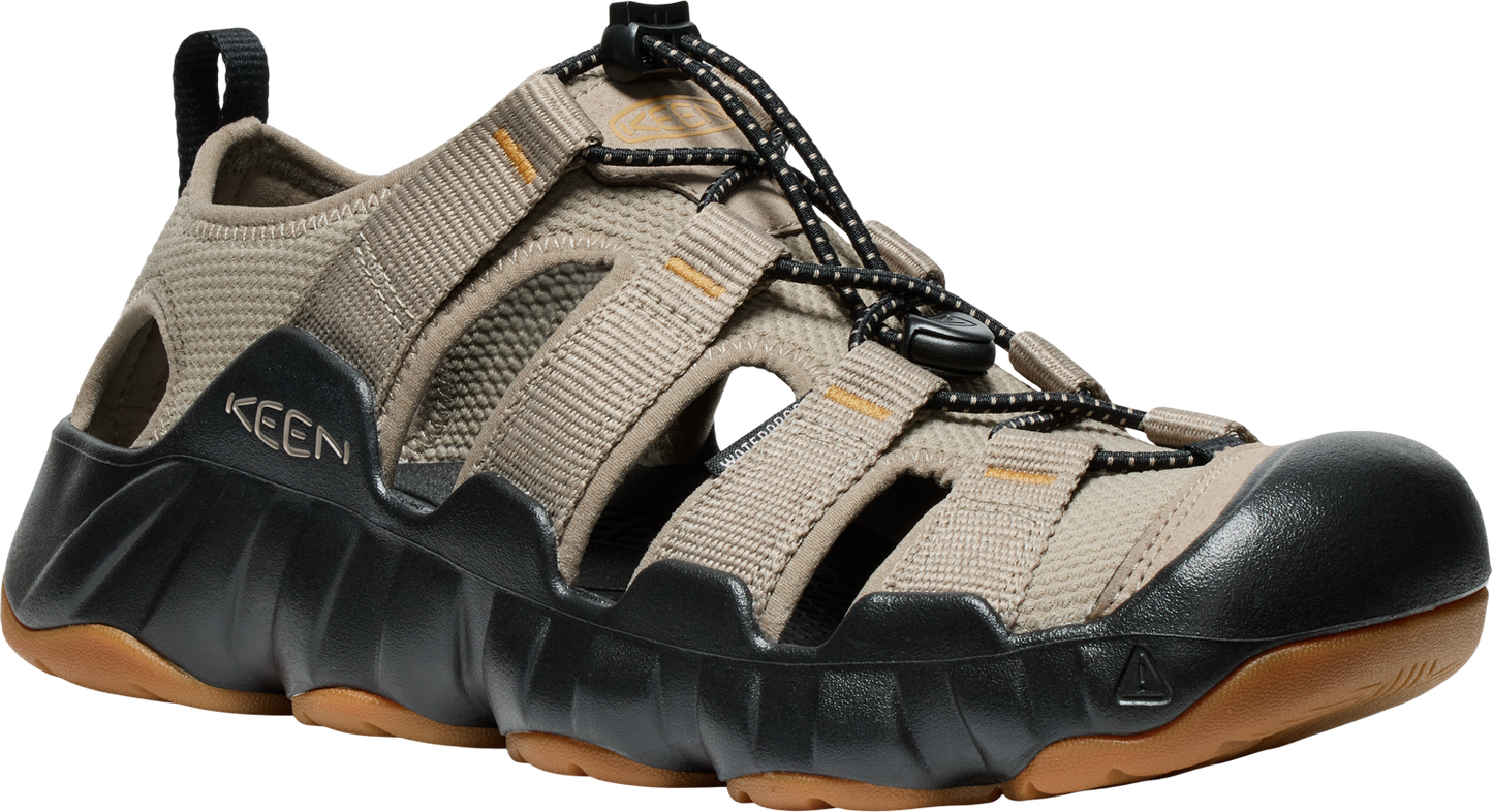 Tan hybrid sandal with black accents, elastic laces, open slots, and thick lug sole. "KEEN" is visible on the upper.