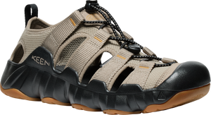 Tan hybrid sandal with black accents, elastic laces, open slots, and thick lug sole. "KEEN" is visible on the upper.