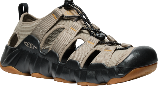Tan hybrid sandal with black accents, elastic laces, open slots, and thick lug sole. "KEEN" is visible on the upper.