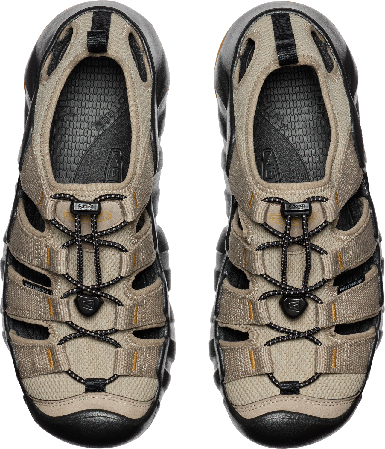 Overhead view of two closed-toe sandals in tan and black with a bungee cord lacing system.