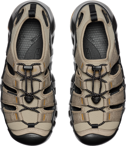 Overhead view of two closed-toe sandals in tan and black with a bungee cord lacing system.