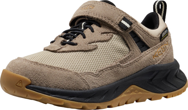 A low-profile tan-colored shoe with black laces, a velcro strap, a black sole, and a brown toe cap.