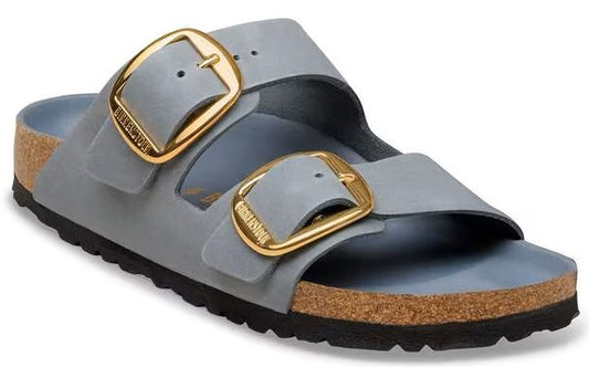 Light blue sandal slide with two straps and large gold buckles, with a cork footbed and black sole.