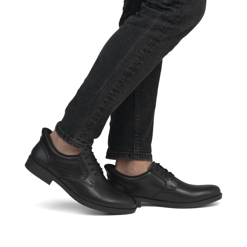 Person wearing black jeans and black leather dress shoes.