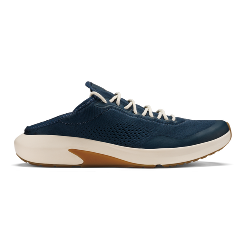 A slip-on sneaker in dark navy blue with a breathable perforated upper, off-white laces, and a thick off-white midsole with a gum-colored rubber insert at the heel.