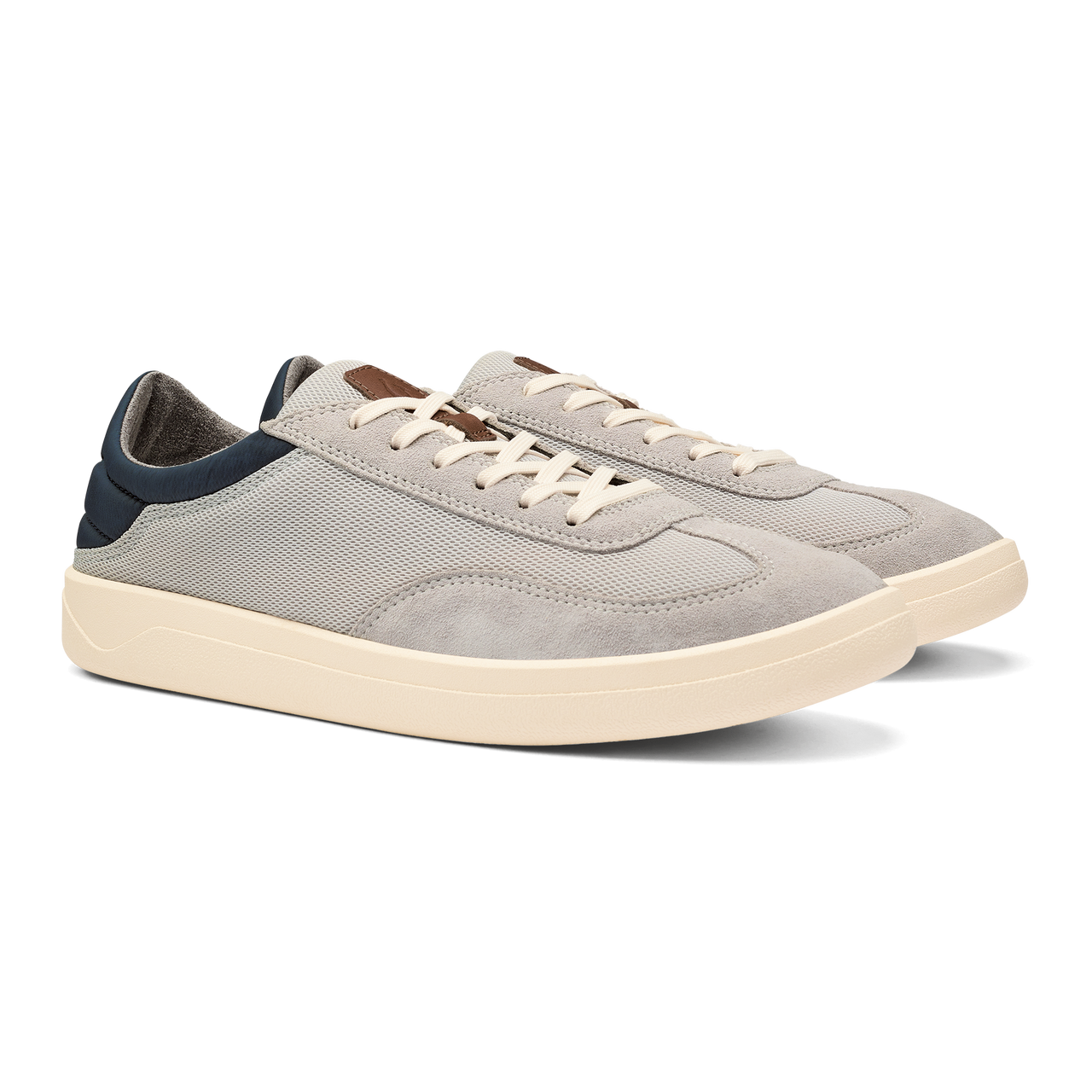 A pair of low-top sneakers in light gray suede and mesh with off-white midsoles, white laces, and navy blue heel accents.