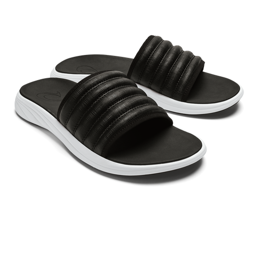 Two black slide sandals with ribbed straps and white soles.
