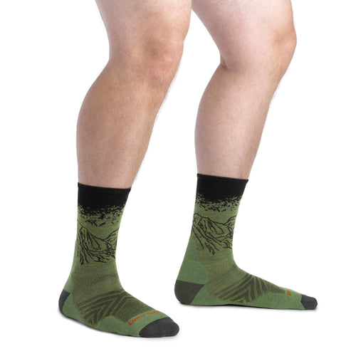 Person wearing green socks with a mountain design and black cuff and toe.