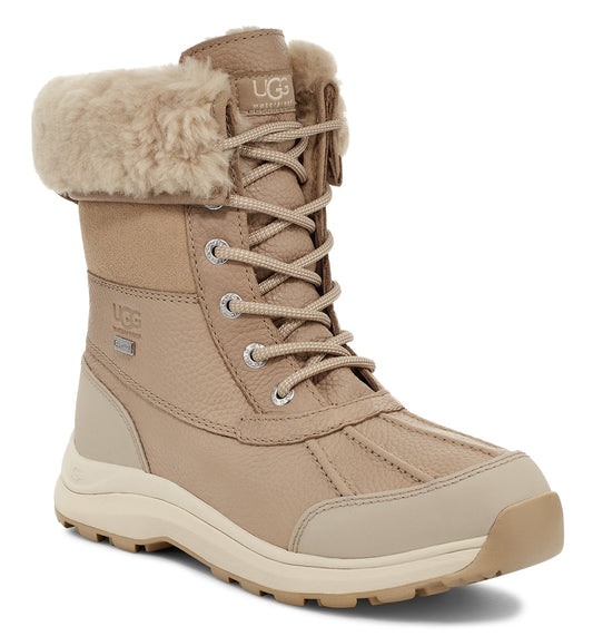 Tan-colored UGG boot with faux fur trim and laced front.