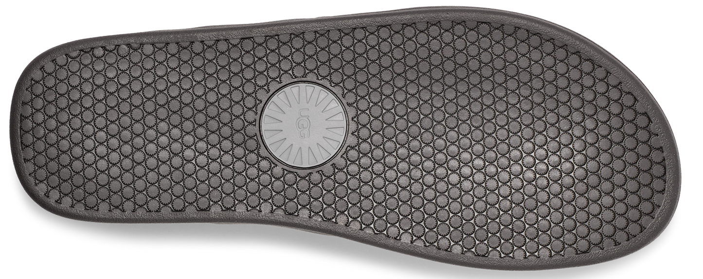A gray shoe sole with a honeycomb pattern and circular logo in the middle.