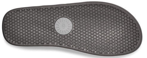 A gray shoe sole with a honeycomb pattern and circular logo in the middle.
