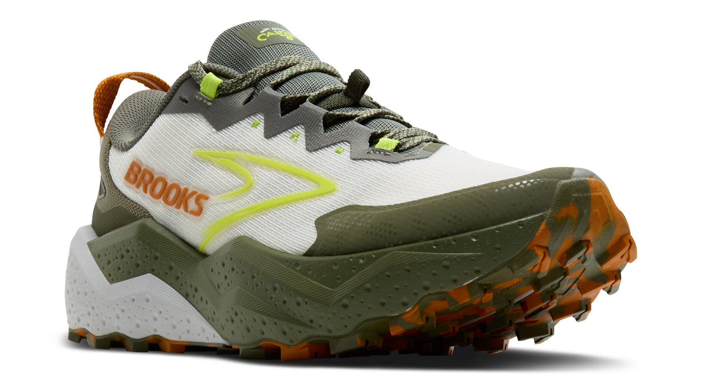 A white, green, and orange trail running shoe with a lugged outsole and the word "BROOKS" printed on the side.