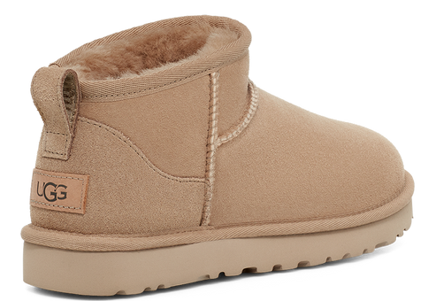 Ankle height, beige UGG boot with a sheepskin lining and loop pull at the back of the heel.