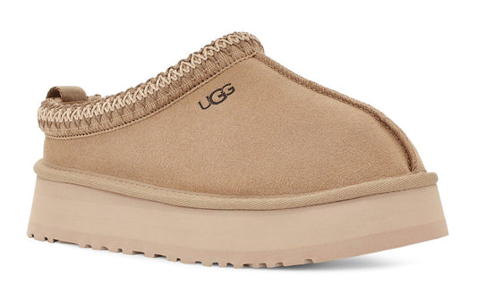 Slip-on shoe with a thick sole, taupe upper with woven top, and "UGG" printed on the side.