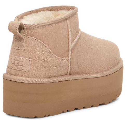 Close up of a light brown suede boot with a light brown platform sole and UGG logo.