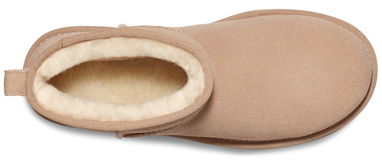 A tan, short bootie with white fur lining visible around the ankle opening.