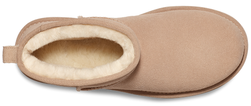 A tan, short bootie with white fur lining visible around the ankle opening.