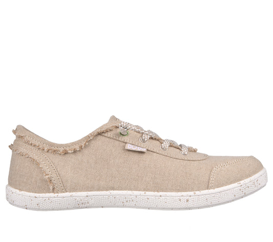 Beige canvas sneaker with a fringed heel and white laces.