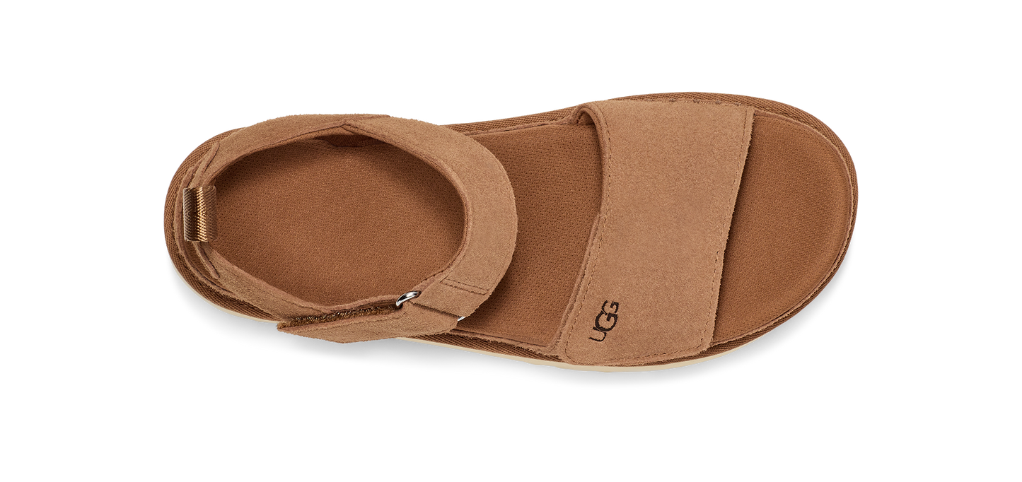 A tan-colored sandal with two wide straps, one around the toes and one around the ankle, and the letters 'UGG' on the side.