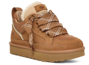 Tan suede sneaker with a thick sole and a plaid, wide lace-up closure and a tan patch that reads UGG.