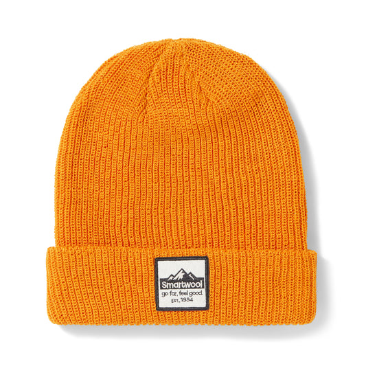 Knitted beanie in golden hue with folded brim and square logo reading "Smartwool go far, feel good est. 1994".