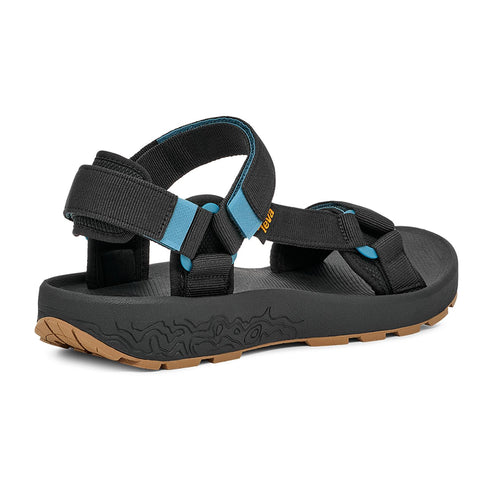 A black sandal with light blue accents, with a black sole and brown patterned bottom.