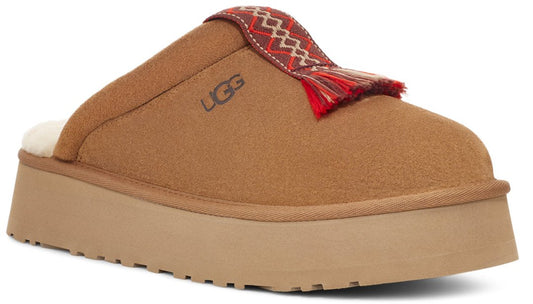 A tan suede slipper mule with a platform sole and a red tassel detail with an embroidered band.