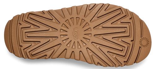 Close-up of the sole of a light brown shoe with the word "UGG" in the center of a circular pattern.