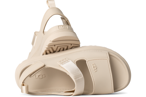 Pair of off-white UGG sandals, one on its side with the sole visible.