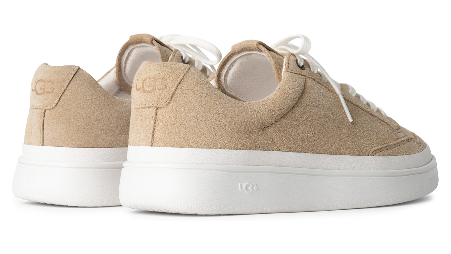 Low-profile, tan suede sneakers with white laces and thick white soles.