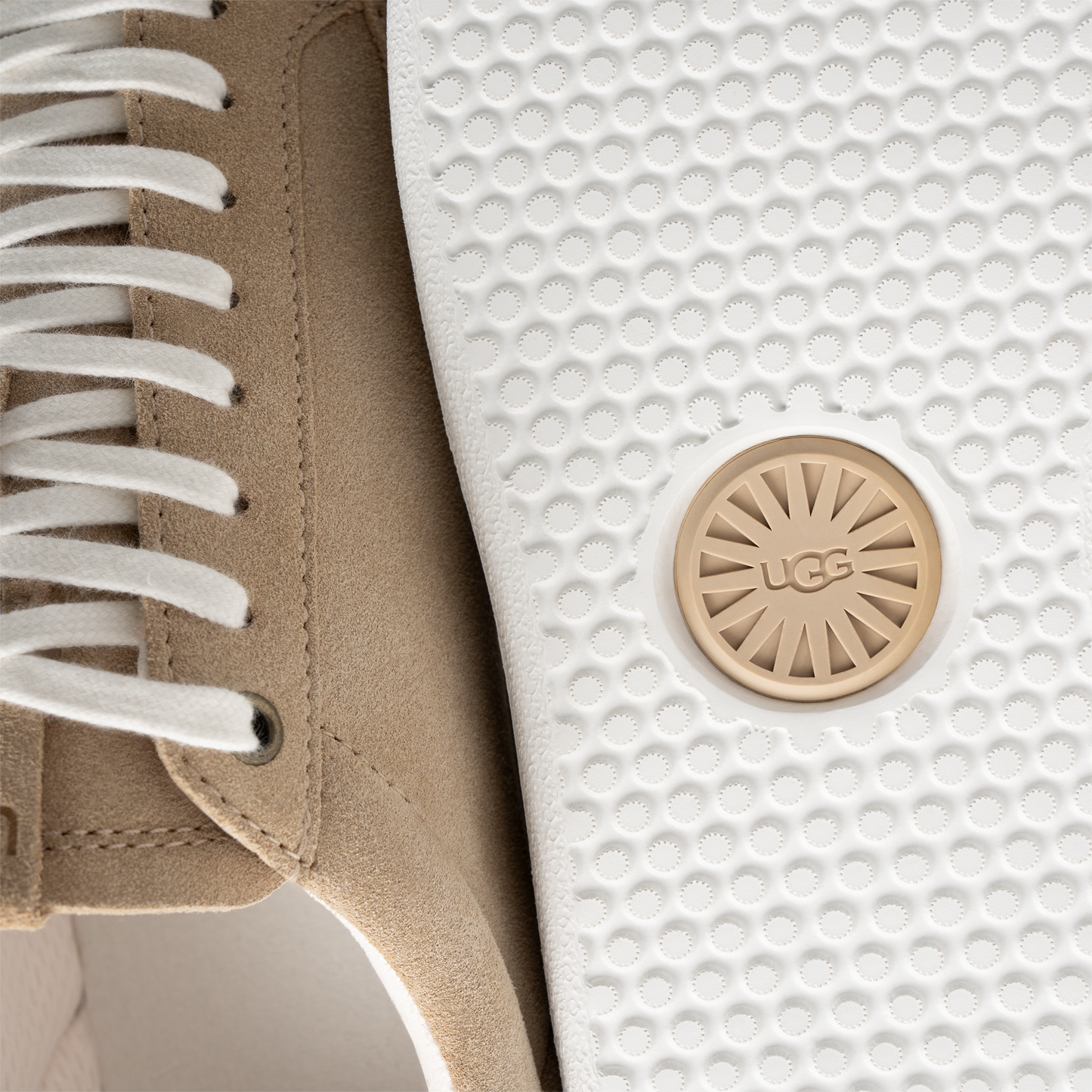 Tan suede high-top sneaker with white laces, and a white sole with a beige logo circle.