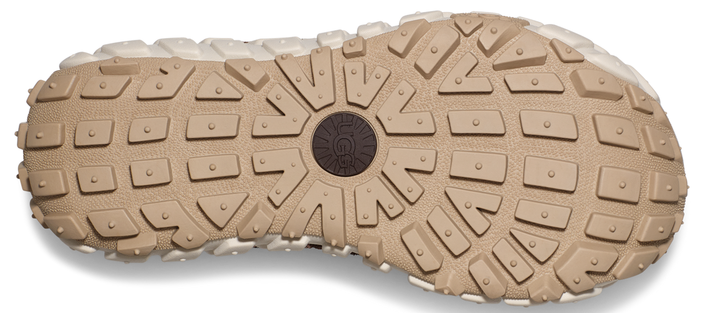 The outsole of a light brown shoe features a pattern of rectangular and triangular treads with circular details in the center.