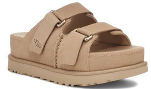 A tan-colored platform sandal with two adjustable straps and the letters 'UGG' on the left strap.