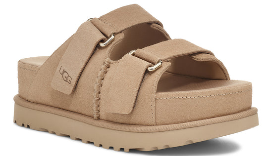 A tan-colored platform sandal with two adjustable straps and the letters 'UGG' on the left strap.