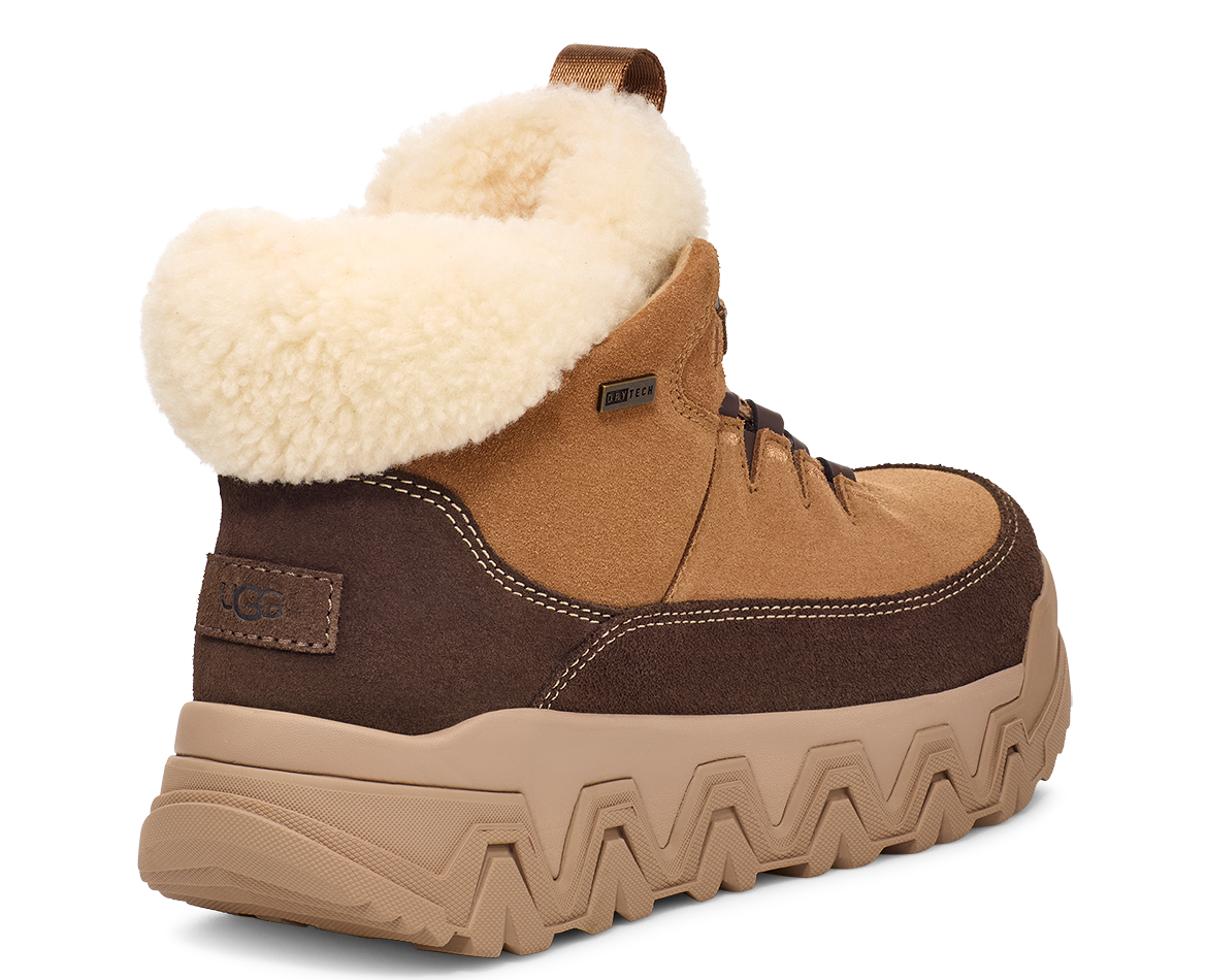 Side view of a brown UGG boot with a tan platform sole and a cream-colored sheepskin lining.