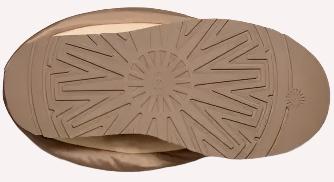 Close-up of the sole of a tan slipper. The sole has circular treads in the center and angled treads at the perimeter.