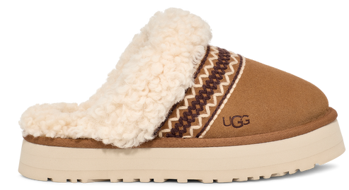 Tan suede slipper with cream-colored sheepskin trim and thick platform sole; a native-inspired design and the letters 'UGG' decorate the side.