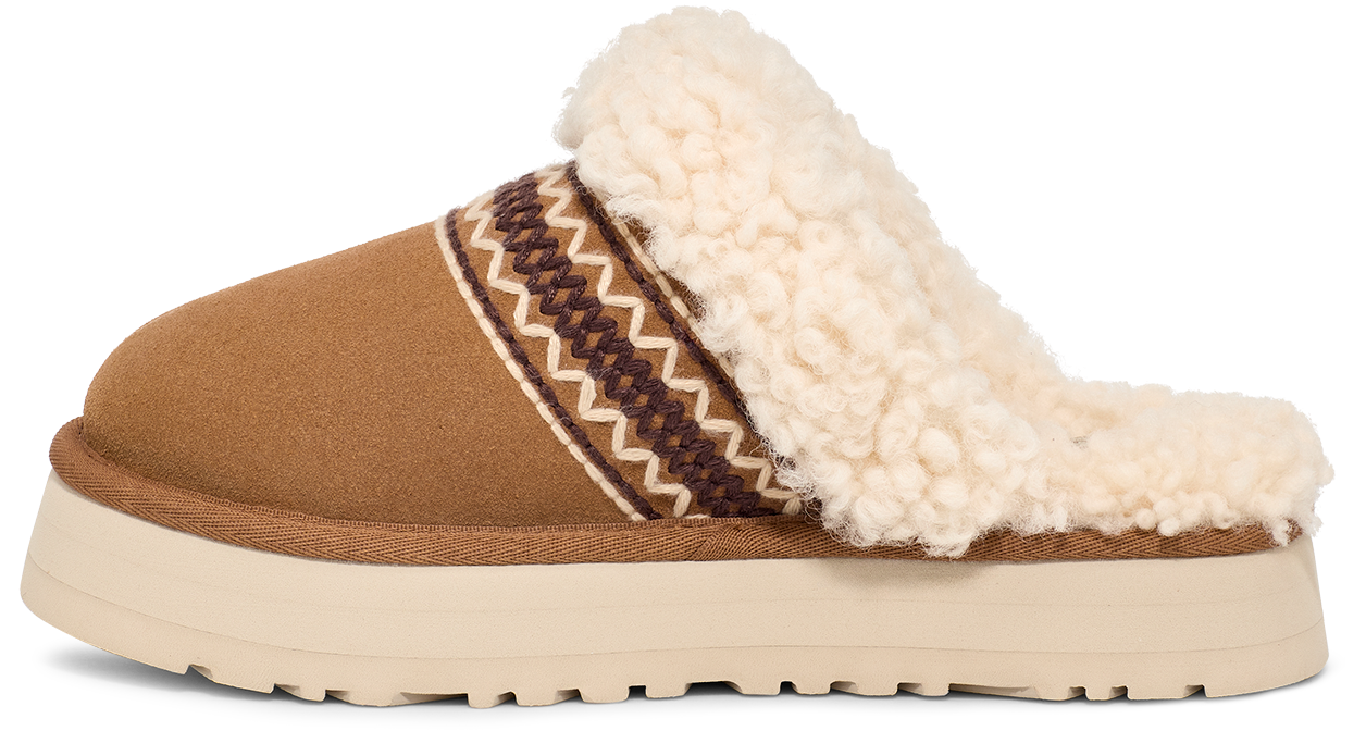 Tan suede slipper with white sherpa lining and trim, decorative patterned band, and a white platform sole.